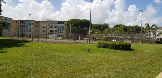 view of property's community featuring tennis court and a yard