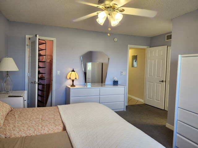 carpeted bedroom with ceiling fan and a textured ceiling