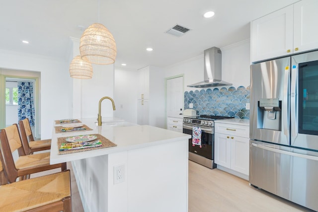 kitchen featuring wall chimney exhaust hood, decorative light fixtures, white cabinets, backsplash, and appliances with stainless steel finishes