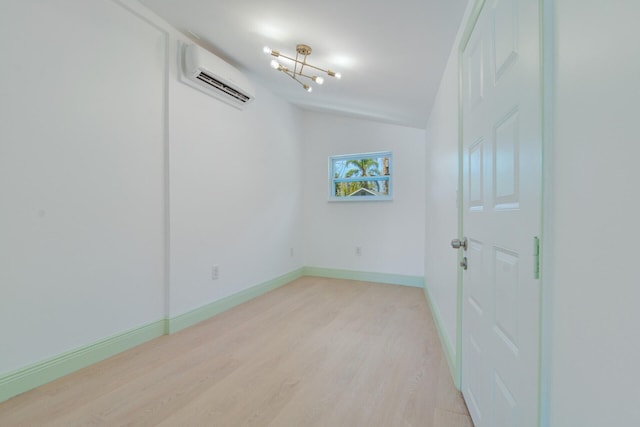 empty room with a wall mounted air conditioner, vaulted ceiling, and light wood-type flooring