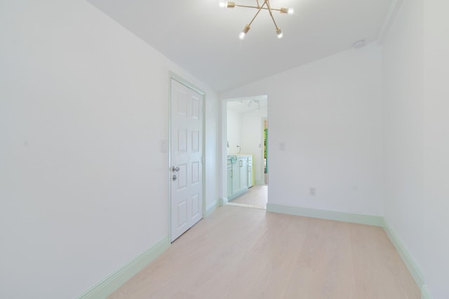 empty room with light hardwood / wood-style flooring, lofted ceiling, and an inviting chandelier