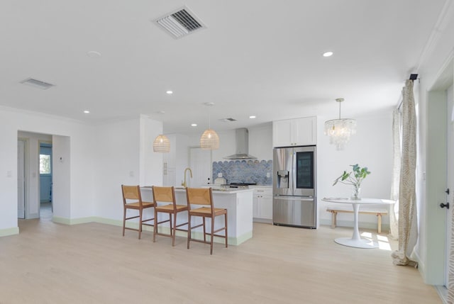 kitchen featuring tasteful backsplash, light hardwood / wood-style flooring, white cabinetry, a center island with sink, and stainless steel fridge with ice dispenser