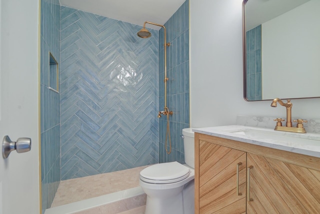 bathroom with vanity, toilet, and tiled shower