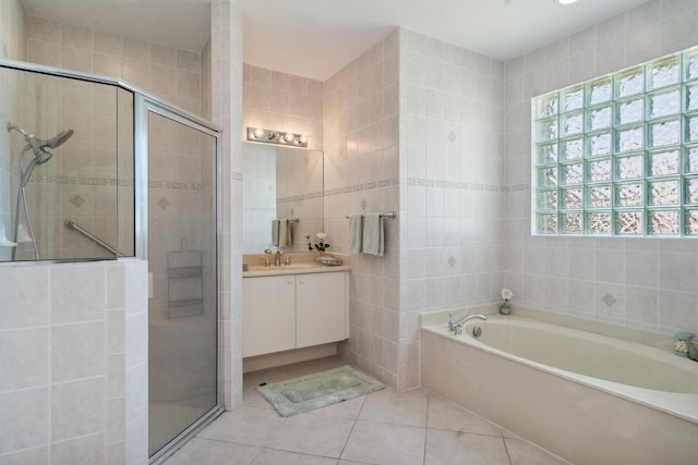 bathroom with independent shower and bath, vanity, tile floors, and tile walls