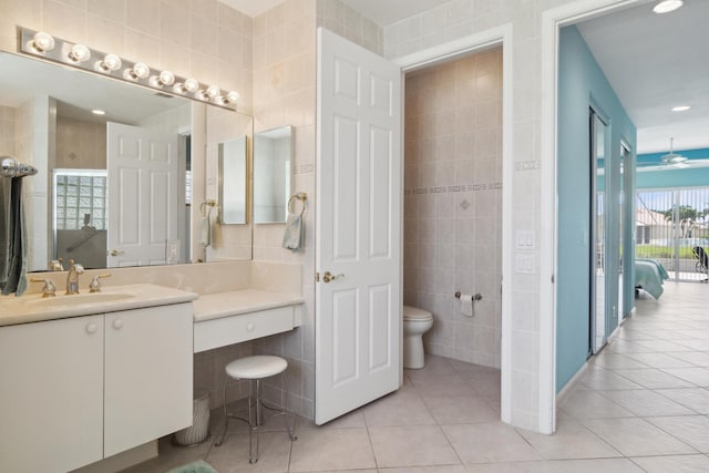 bathroom with vanity, toilet, tile floors, and tile walls