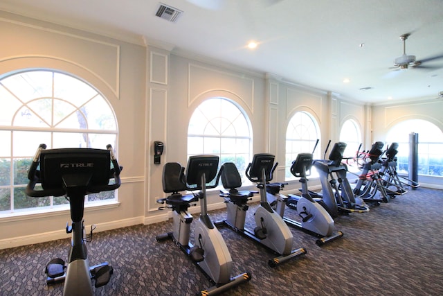 gym featuring plenty of natural light, dark colored carpet, and crown molding