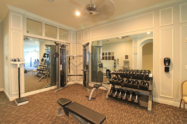 gym with ornamental molding, ceiling fan, and dark carpet