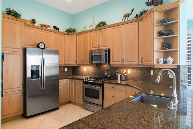 kitchen with appliances with stainless steel finishes, light tile floors, sink, backsplash, and dark stone counters