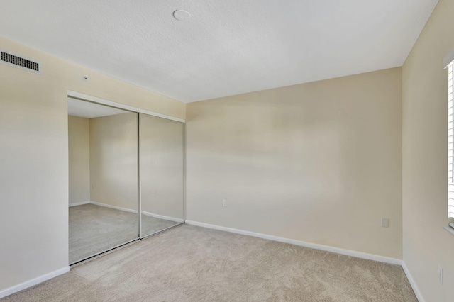 unfurnished bedroom with light colored carpet and a closet