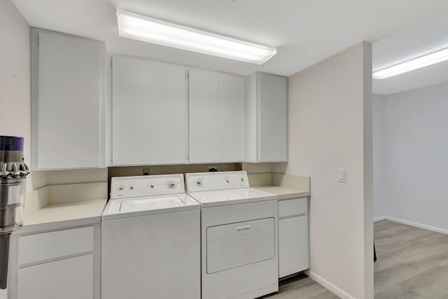 washroom with light wood-type flooring, washer and dryer, and cabinets