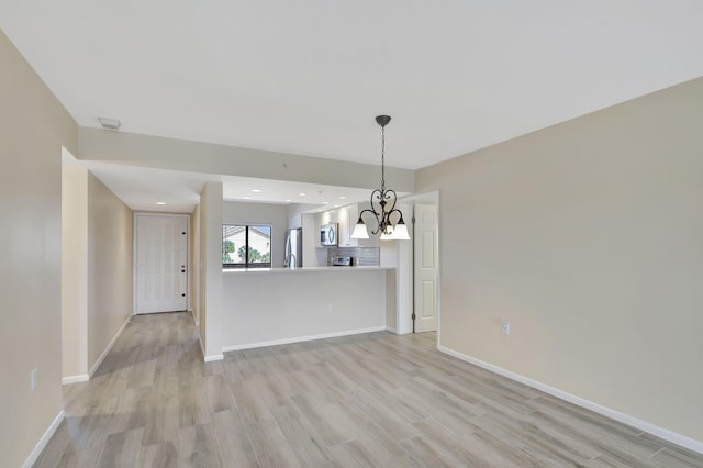 empty room with a notable chandelier and light wood-type flooring