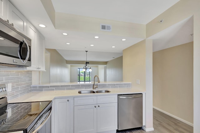 kitchen featuring sink, white cabinetry, hanging light fixtures, stainless steel appliances, and light hardwood / wood-style flooring