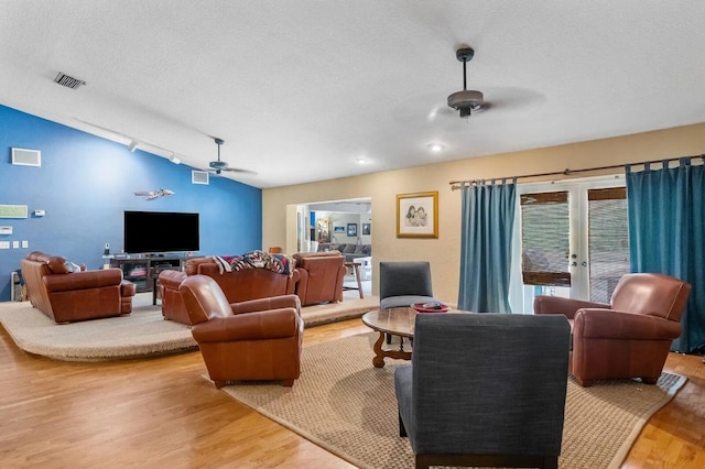 living room featuring ceiling fan, vaulted ceiling, a textured ceiling, and track lighting