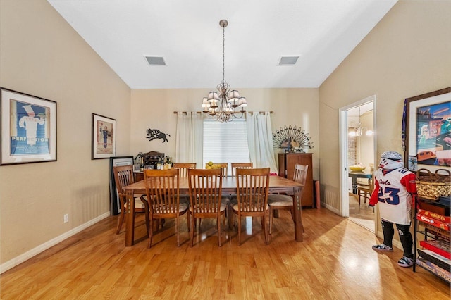 dining area with a notable chandelier, light hardwood / wood-style flooring, and lofted ceiling