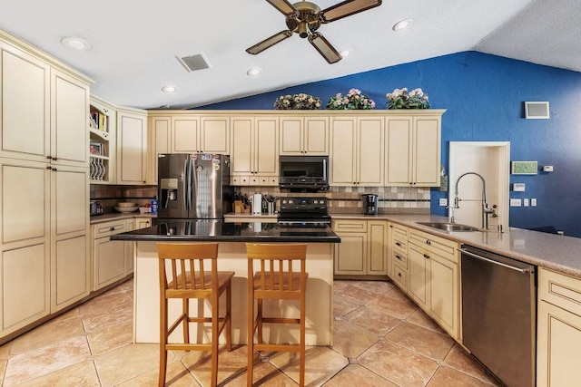 kitchen featuring a kitchen breakfast bar, ceiling fan, stainless steel appliances, vaulted ceiling, and backsplash