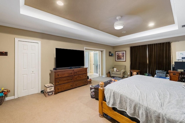 bedroom featuring light carpet, a tray ceiling, and ceiling fan