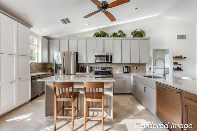 kitchen with light stone countertops, ceiling fan, vaulted ceiling, light tile flooring, and appliances with stainless steel finishes