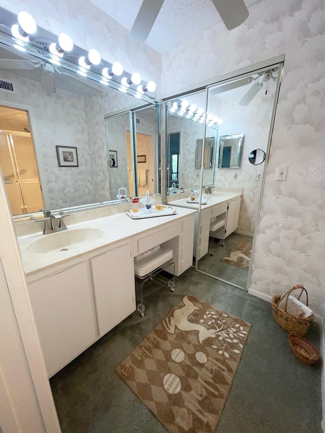 bathroom featuring double sink vanity, ceiling fan, and a textured ceiling