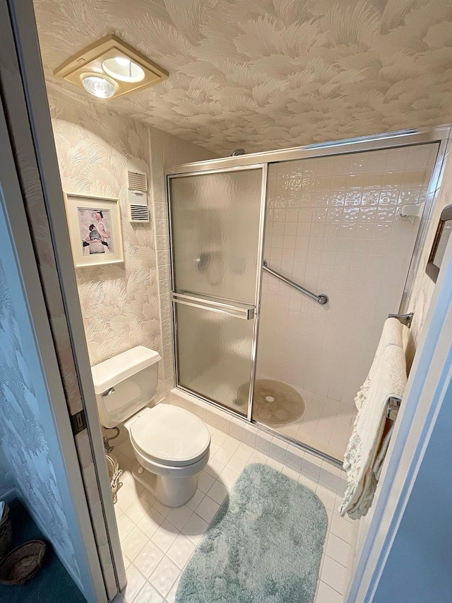 bathroom with a shower with shower door, toilet, and tile floors