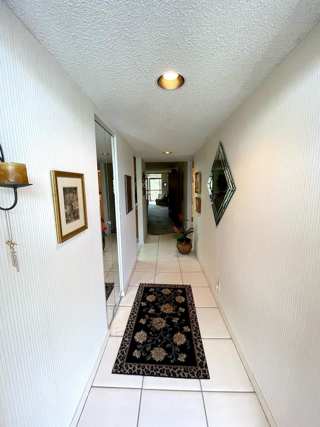 corridor with light tile floors and a textured ceiling