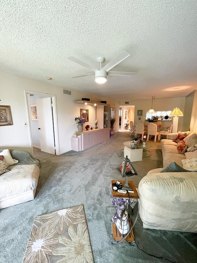 living room with carpet flooring, ceiling fan, and a textured ceiling