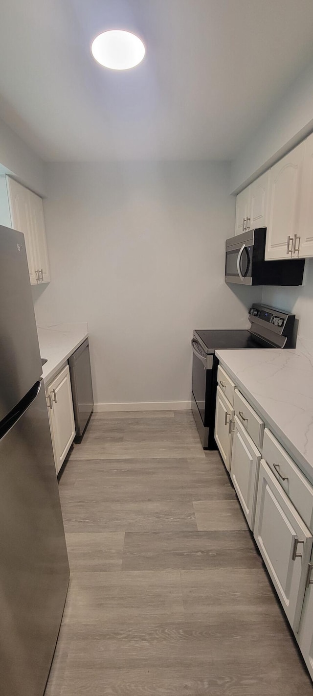 kitchen featuring stainless steel appliances, white cabinets, and light wood-type flooring