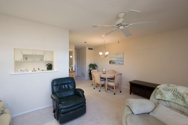 living room featuring ceiling fan with notable chandelier and light colored carpet