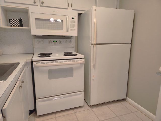 kitchen featuring light tile patterned floors, white appliances, white cabinetry, and sink