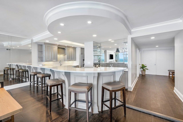 kitchen featuring kitchen peninsula, crown molding, a breakfast bar, and dark hardwood / wood-style floors