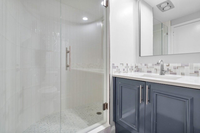 bathroom featuring tasteful backsplash, vanity, and a shower with shower door