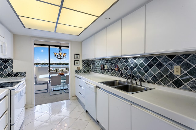 kitchen with white cabinets, an inviting chandelier, white appliances, sink, and decorative backsplash