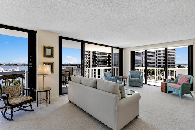 living room with a textured ceiling, a water view, floor to ceiling windows, and light colored carpet