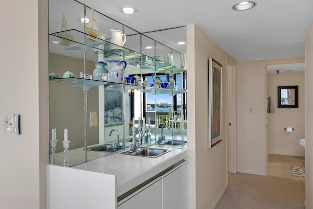 bar featuring white cabinetry, sink, and light colored carpet