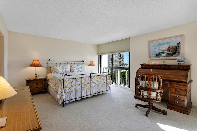 bedroom featuring a textured ceiling, access to outside, and light colored carpet