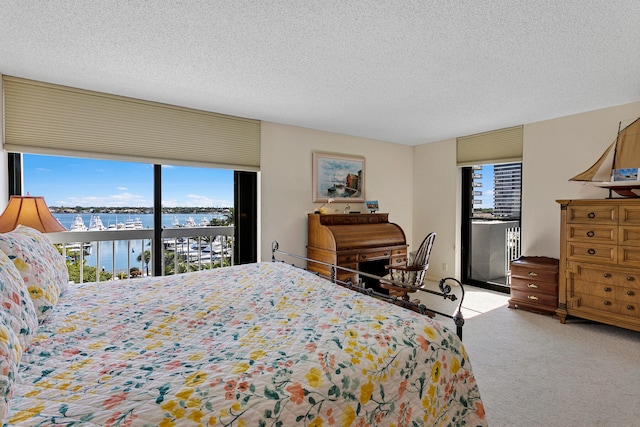 bedroom featuring a water view, carpet flooring, access to outside, and a textured ceiling