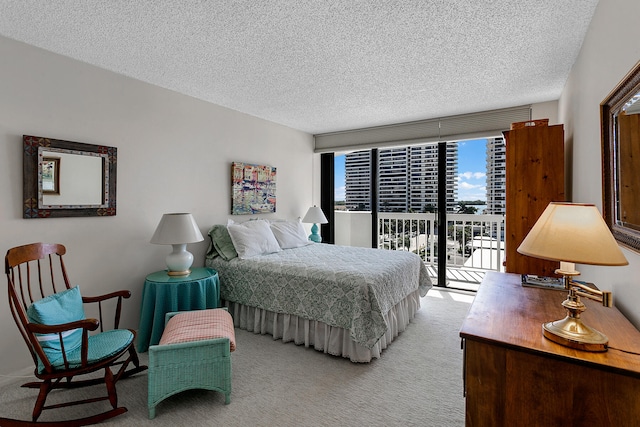 bedroom featuring a textured ceiling, access to exterior, and light colored carpet