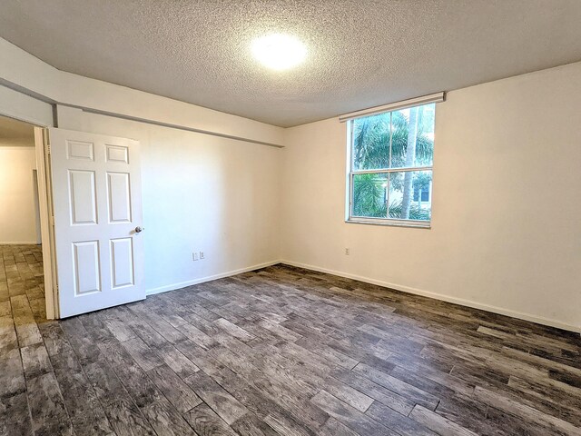 unfurnished room with dark wood-type flooring and a textured ceiling