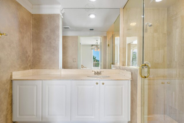 bathroom featuring walk in shower, ceiling fan, vanity with extensive cabinet space, and ornamental molding