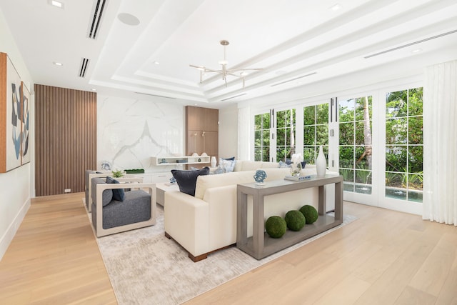 living room with light hardwood / wood-style floors, a chandelier, and a tray ceiling