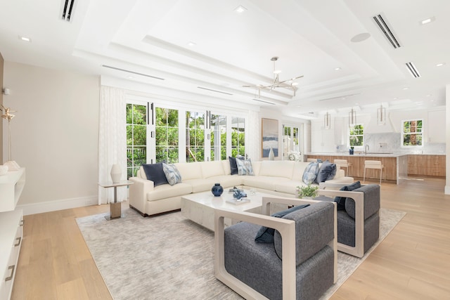 living room featuring a tray ceiling and light hardwood / wood-style floors