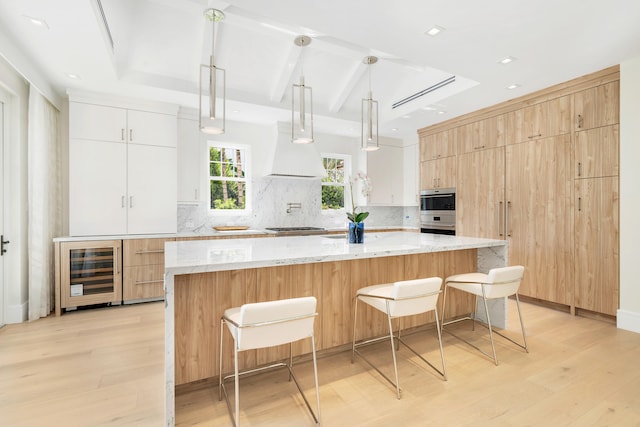 kitchen featuring white cabinetry, wine cooler, light stone counters, decorative light fixtures, and light wood-type flooring