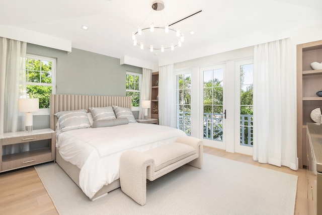 bedroom featuring access to outside, wood-type flooring, and a chandelier