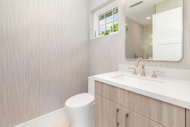 bathroom with walk in shower, vanity, and toilet