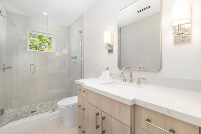 bathroom featuring a shower with shower door, vanity, and toilet