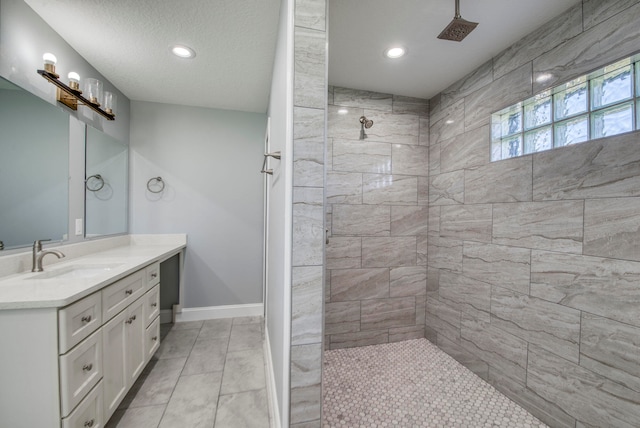 bathroom featuring tile patterned flooring, vanity, a textured ceiling, and tiled shower