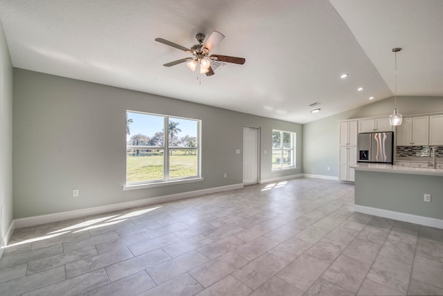 unfurnished living room featuring plenty of natural light, ceiling fan, lofted ceiling, and sink