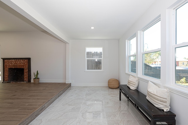 sitting room with a brick fireplace and light wood-type flooring