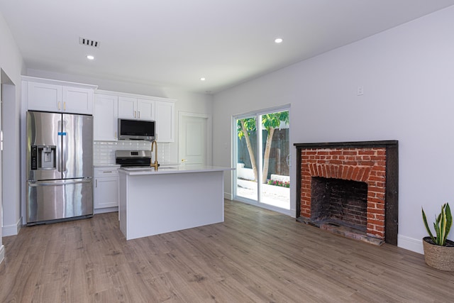 kitchen featuring tasteful backsplash, stainless steel appliances, light hardwood / wood-style floors, and white cabinetry