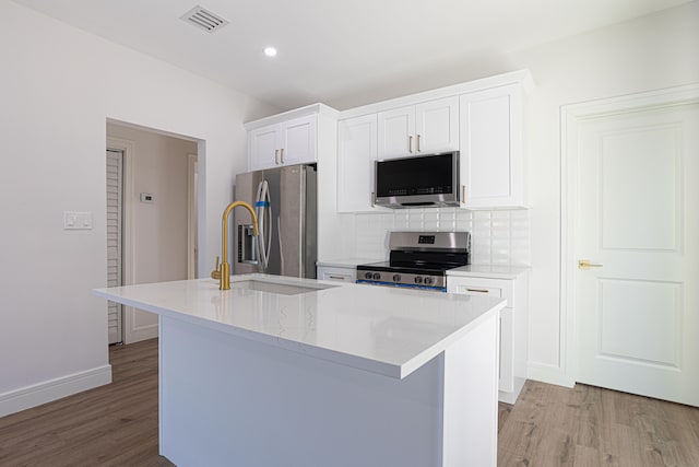 kitchen featuring light hardwood / wood-style flooring, stainless steel appliances, an island with sink, and white cabinetry