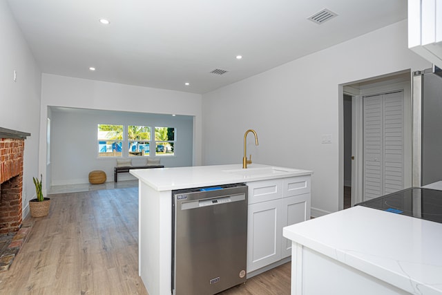 kitchen featuring light hardwood / wood-style floors, a brick fireplace, white cabinets, and stainless steel dishwasher